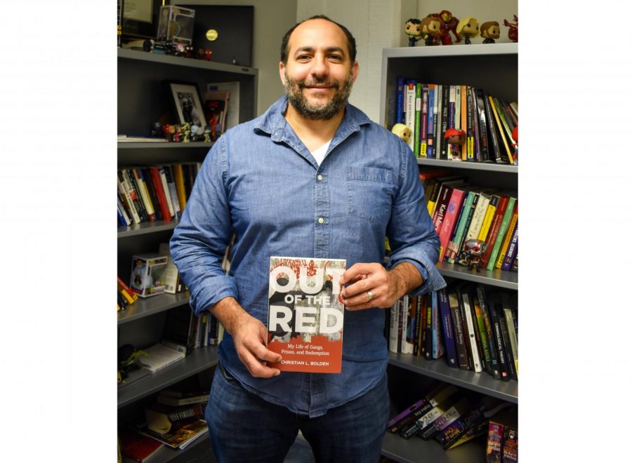 Criminology professor, Christian Bolden holds his new book Out of the Red in his office. Boldens memoir included details of his traumatic youth and his path to becoming a Loyola professor. Maria Paula Mariño /The Maroon Photo credit: Maria Paula Marino