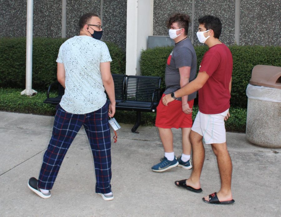 Loyola students Bryan Grassia, Dominic Howell and Adrien Kays walk outside Biever Hall while wearing masks. Wearing masks in public spaces helps to prevent and reduce the spread of COVID-19. Photo credit: Kadalena Housley