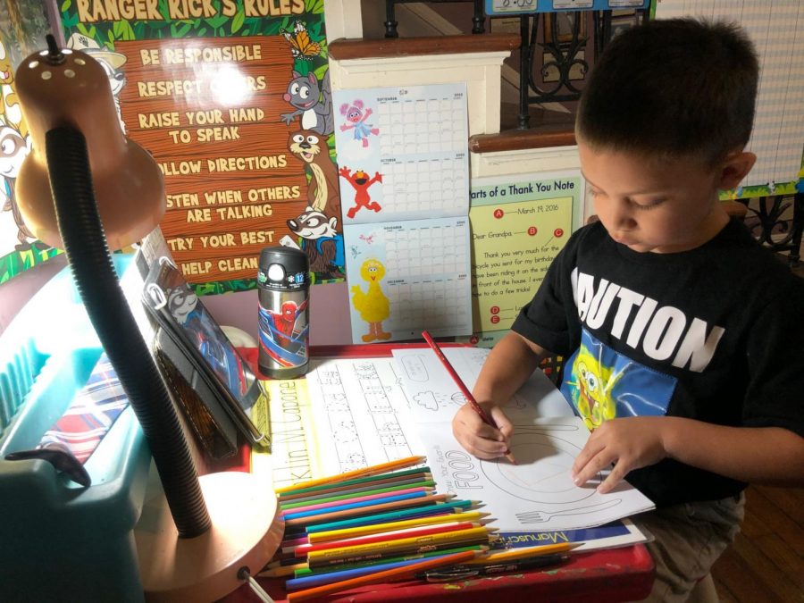 Franklin, the six-year-old son of Megan Braden-Perry, doodles in his homemade classroom. Parents like Braden-Perry are trying to get creative to help their kids cope with going to school online. Photo credit: Megan Braden-Perry