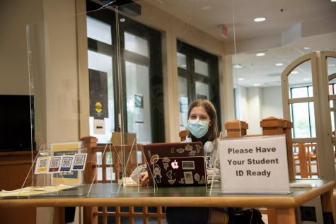 Junior Mary Larson sits at the Monroe Library check-in desk as a student worker in the work study program. Due to COVID-19, the options for work study jobs have changed. Photo credit: Michael Bauer