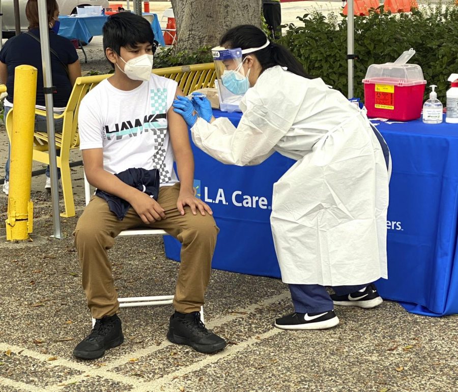 Moises Lopez of Los Angeles receives a flu shot from Jessica Zhou of USC as people receive free flu shots during a walk up and drive thru clinic in Los Angeles on Saturday, Oct. 10, 2020. (Keith Birmingham/The Orange County Register via AP)