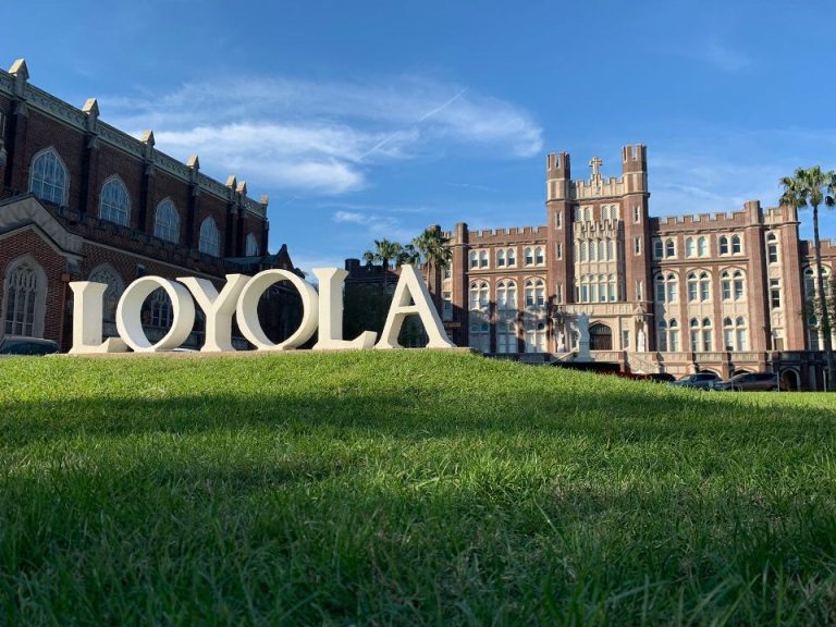 A Loyola sign sits bathed in sunlight outside Marquette Hall. The university has recently updated COVID-19 protocols for the 2022 Fall semester.