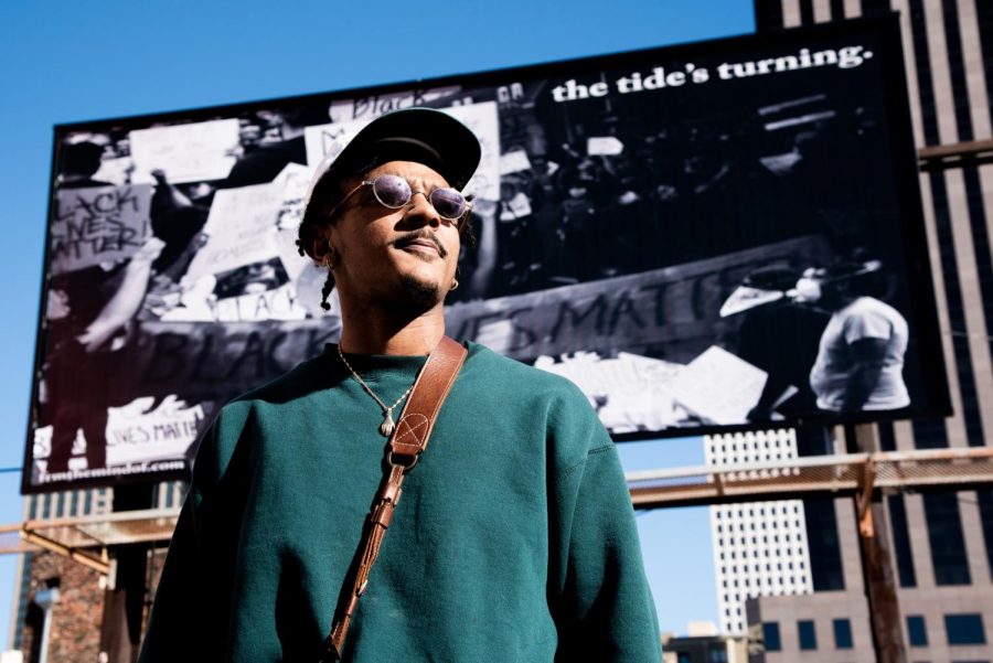 Troy Pierre II poses in front of a billboard featuring his work The Tides Turning.