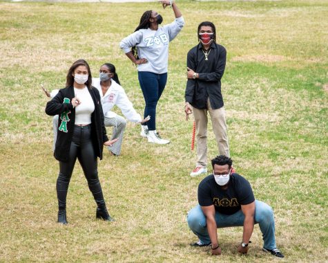 Five members of black fraternities and sororities pose on campus.