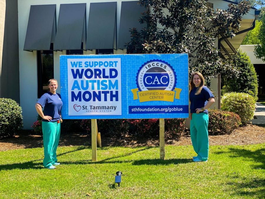 Sunny McDaniel and Dr. McCall McDaniel stand in front of a sign promoting World Autism Month and autism awareness.