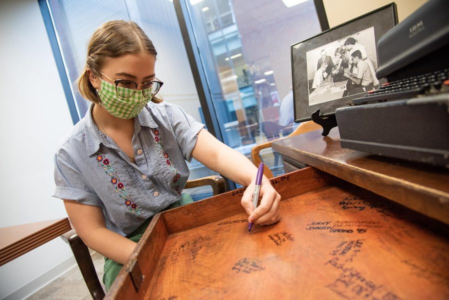 Mass communication senior Rose Wagner signs a desk in the offices of The Maroon. As outgoing editor-in-chief, Wagner joined previous editors-in-chief in signing the desk at the end of her time leading the newsroom.