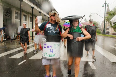 Two New Orleans residents walk in the trash parade wearing trash cans