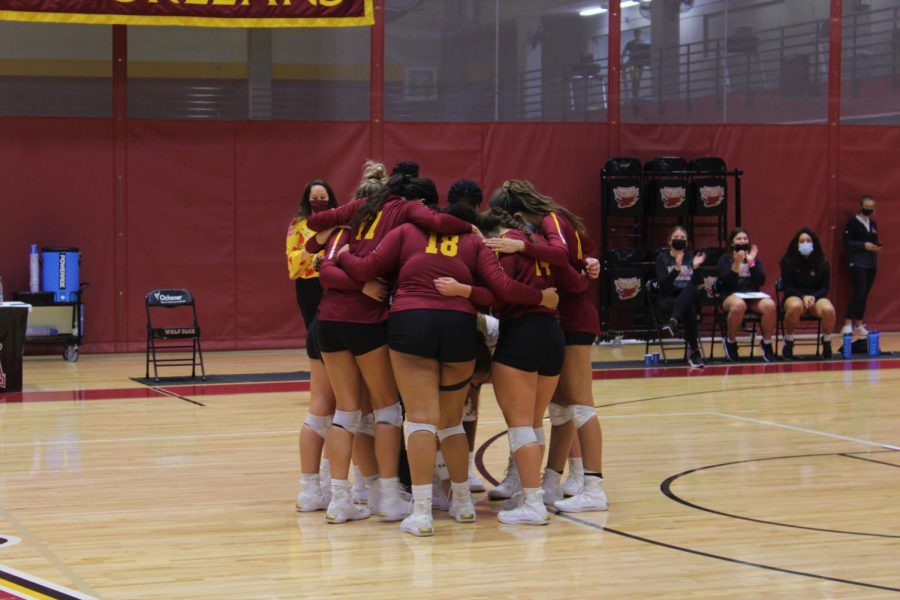 The+Loyola+volleyball+team+in+a+group+huddle+after+scoring+a+point.