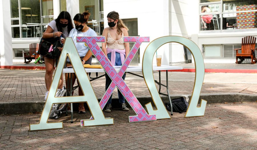 Stephanie Oblena, sophomore environmental studies major, and Nicole Devine, sophomore international business major, talk to a student about sorority events while tabling  for Alpha Chi Omega on Wednesday, Oct. 20, 2021.