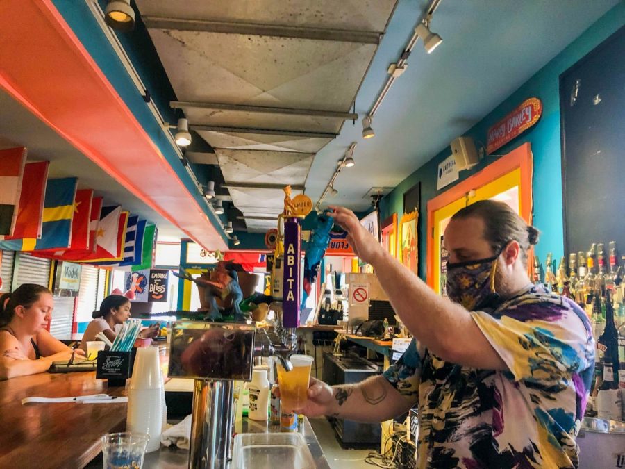 A bartender pours a beer at hot dog restaurant, Dat Dog