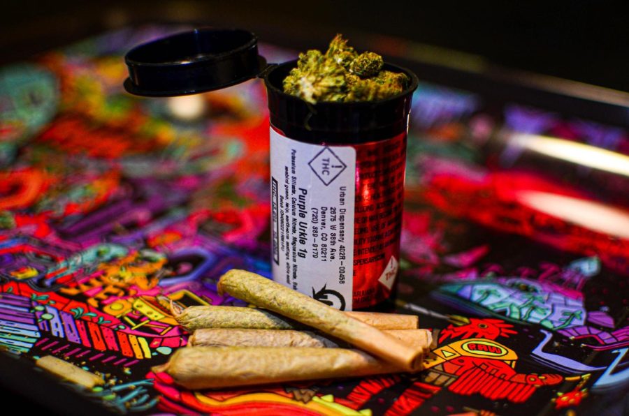 Medical Marijuana in a prescription bottle sits on a psychadelic table beside some rolled joints