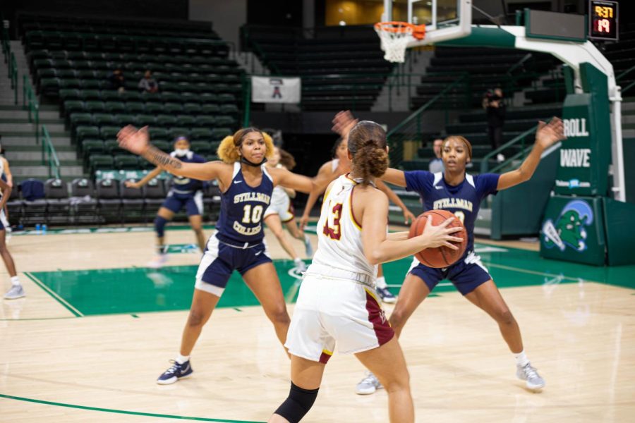 womens basketball team player holds ball and faces two opposing two Stillman defenders