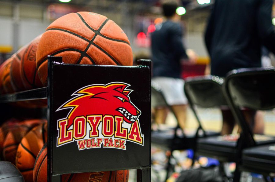 basketballs sit in a Loyola Wolf Pack rack beside the court