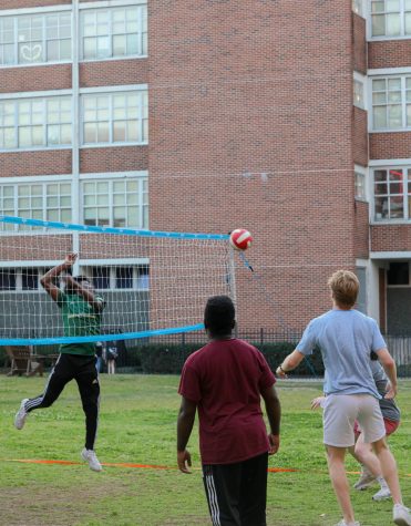 Volleyball player plays the recreational sport in the quad with the ball about to go over the net 