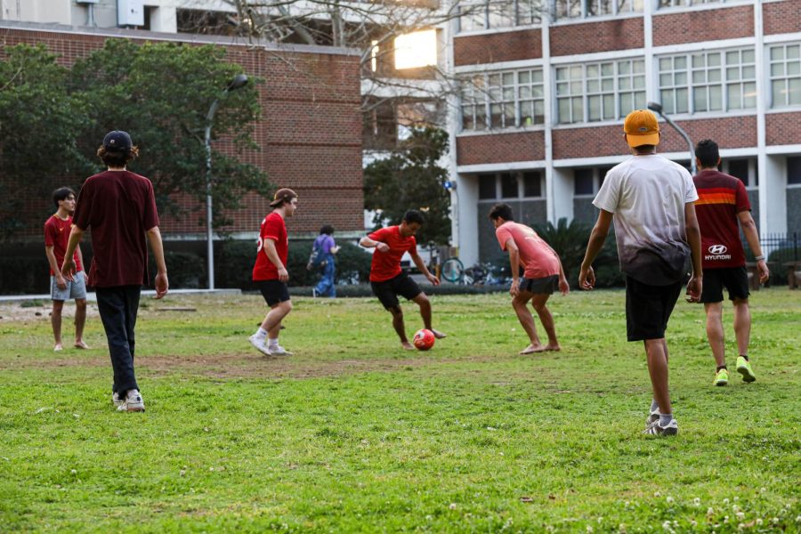 Recreational sport players face inwards towards a soccer player with a ball in the field
