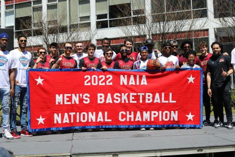 The Loyola mens basketball team holds up a banner that celebrates its championship win on Thursday, March 24 on Loyolas campus. The Wolf Pack won its first NAIA championship since 1945 this week. 