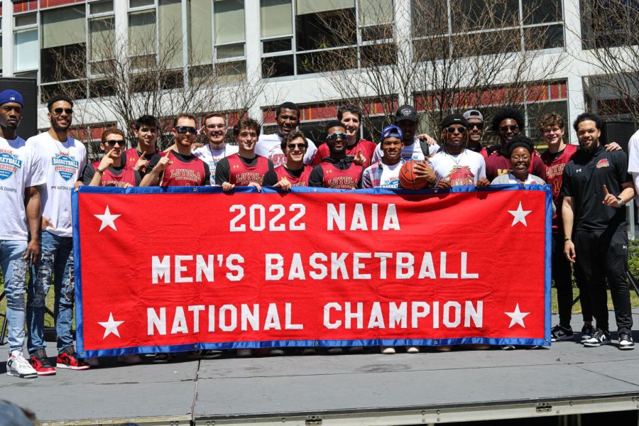 The Loyola men's basketball team holds up a banner that celebrates its championship win on Thursday, March 24 on Loyola's campus. The Wolf Pack won its first NAIA championship since 1945 this week. 