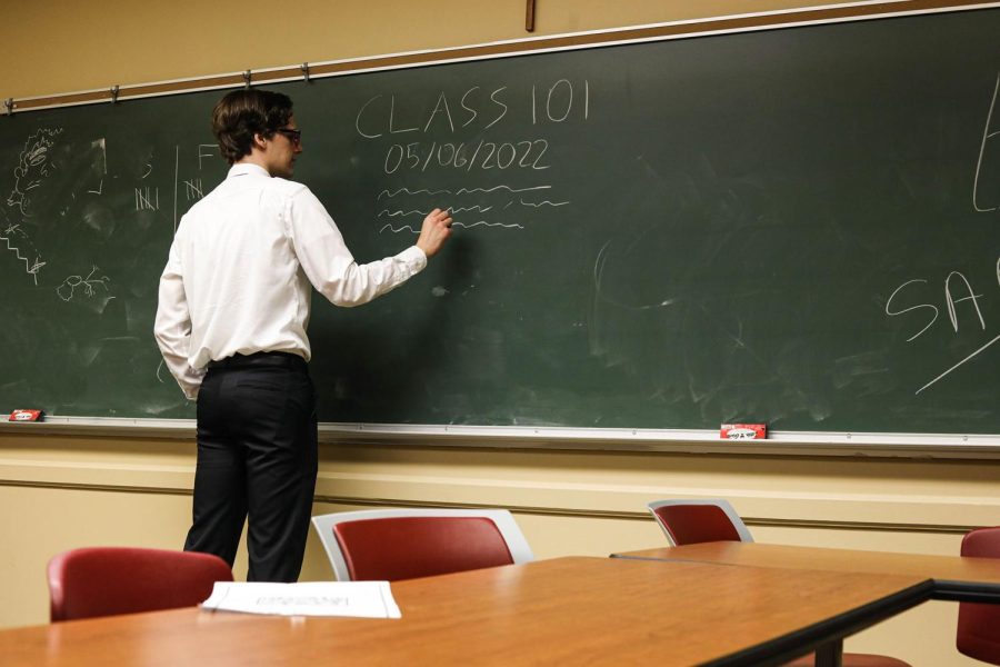 man+writes+on+chalkboard