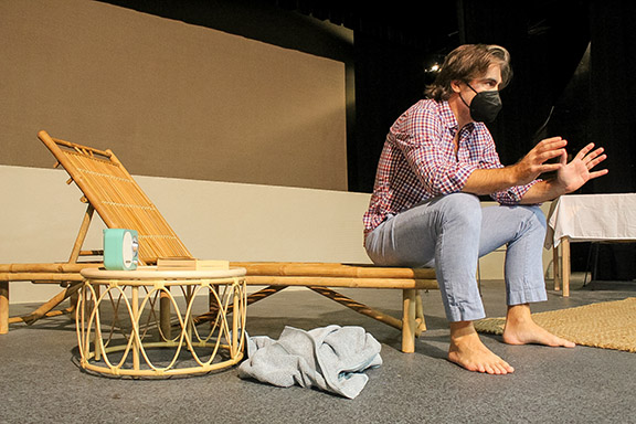 A guy sits on a beach chair on a stage