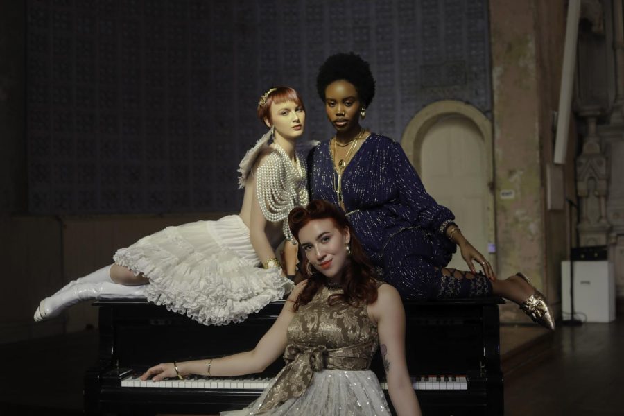 Three models posing in front of a piano