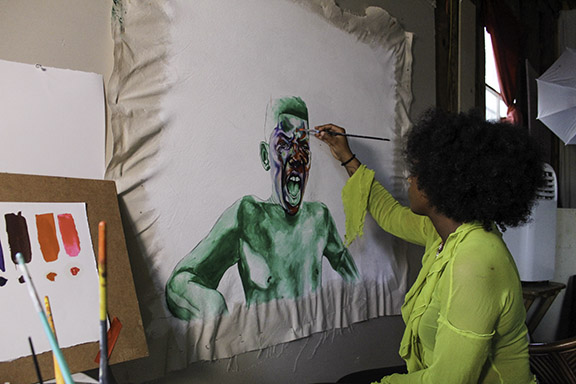 Ri Kailah Mathieu paints a person on a canvas.