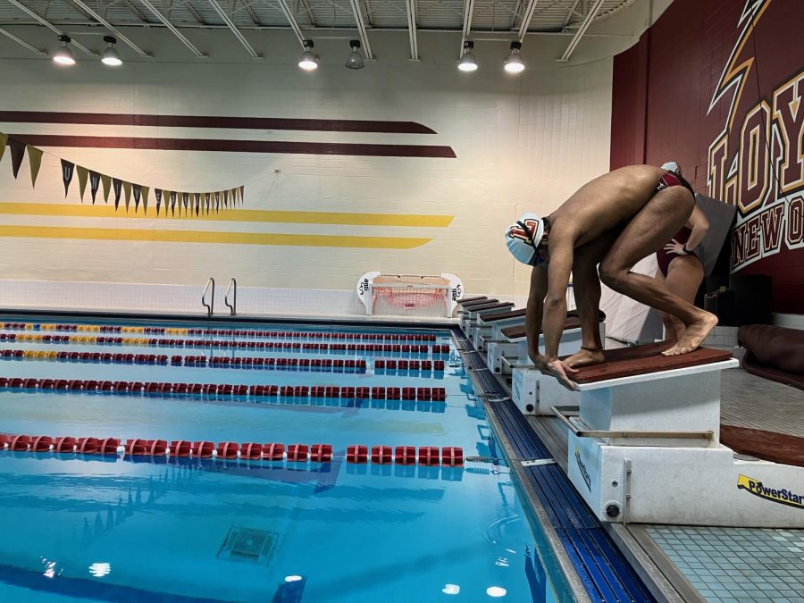 Loyola swimmer on the diving stand getting ready to dive in
