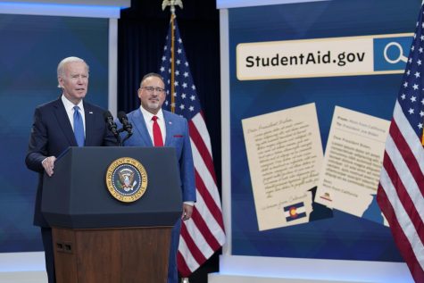 President Joe Biden speaks about the student debt relief portal beta test as Education Secretary Miguel Cardona listens in the South Court Auditorium on the White House complex in Washington, Monday, Oct. 17, 2022. The FBI warns that those seeking loan forgiveness may be targeted in scams.