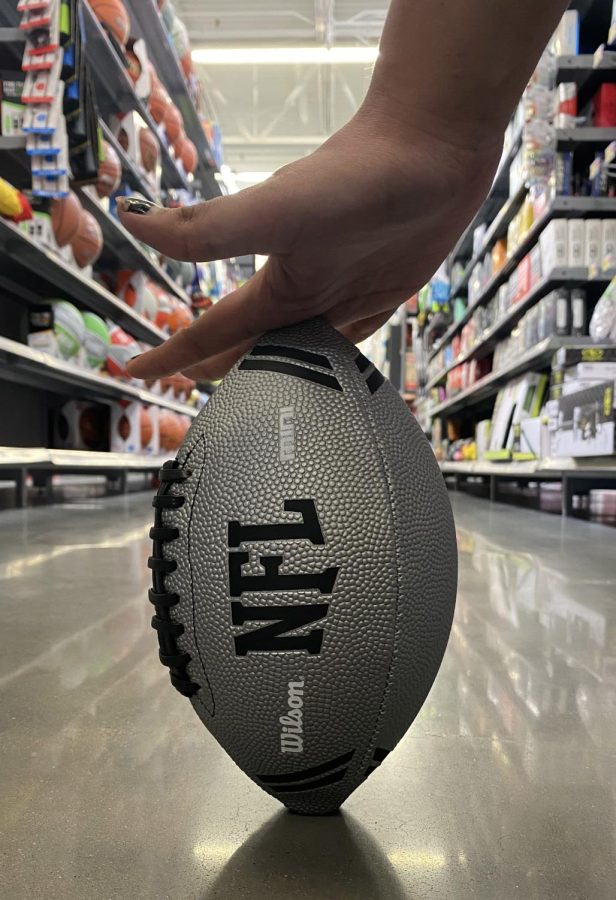 A white, NFL branded football held up in a store aisle.
