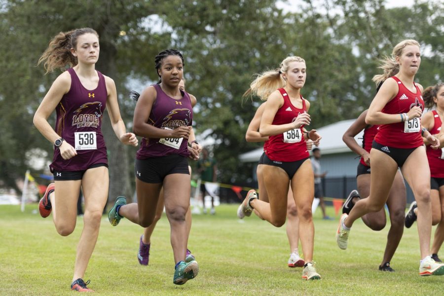 Two Loyola cross country team members run alongside two University of Louisiana Lafayette runners in a race.