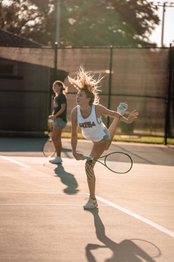 Loyola womens tennis player hits a ball overhead.