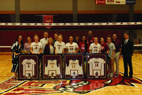 Loyola volleyball seniors stand in the Loyola gym with their framed jerseys