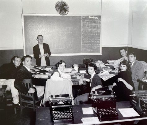 A room full of students sitting in front of typewriters and advisor Ed Frickie in front of a chlakboard