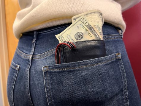 Money sticking out of someones wallet. The wallet is in their back pocket.