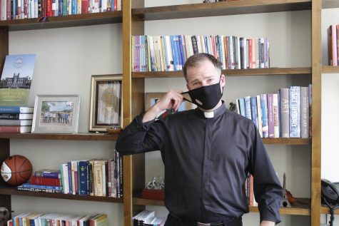 Rev. Justin Daffron, S.J., pulling off his mask in office. Daffron will not be applying for permanent presidential position.