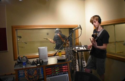 Sophomore Ben Heil stands in a Loyola recording studio playing a guitar.