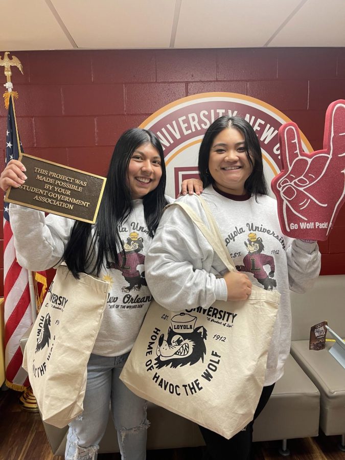 SGA vice president and president stand next to each other while they show off their new merchandise that will be released in March. The merchandise has different logos placed on items like tote bags, hoodies, and foam fingers.
