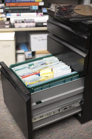 Filing cabinet with bottom drawer drawn out, with multiple files in it.