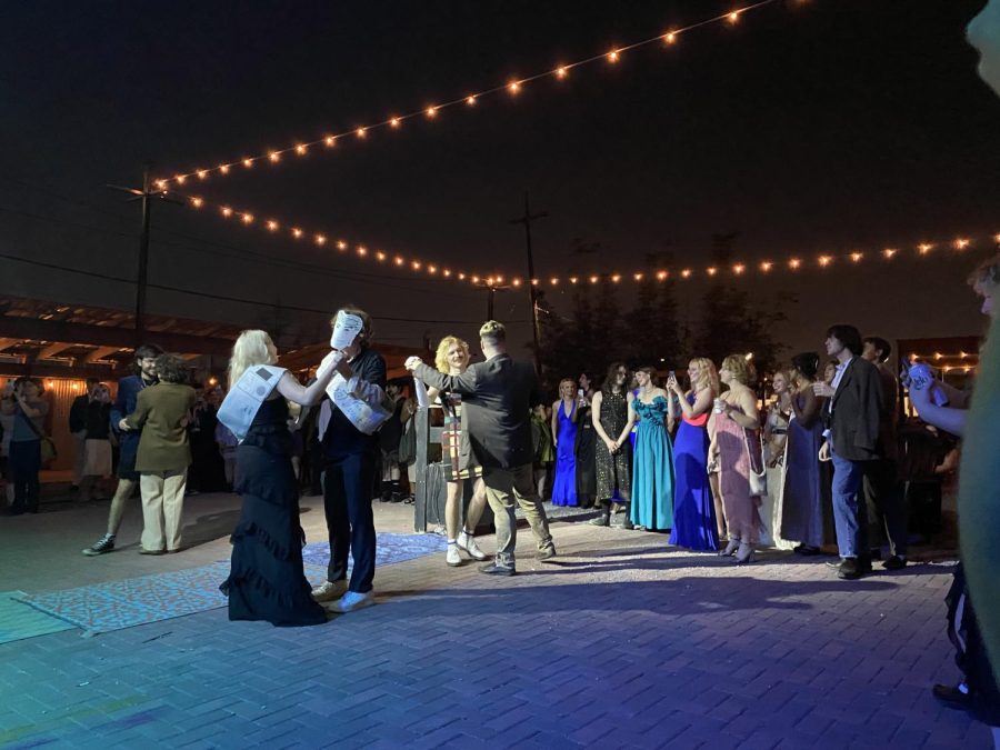 Prom goers in fancy dress slow dance under string lights at the Broadside Theater in New Orleans.