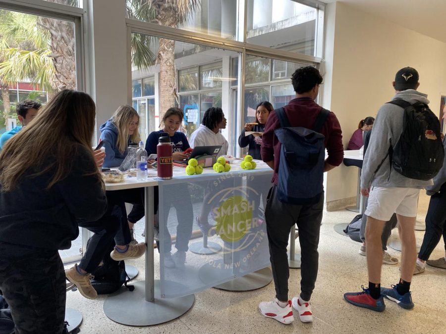 Junior biology major Isabella Isa Leaño (center, smiling) sits at a table in the Danna Center to promote the Smash Cancer Tennis-athon on March 13, 2023