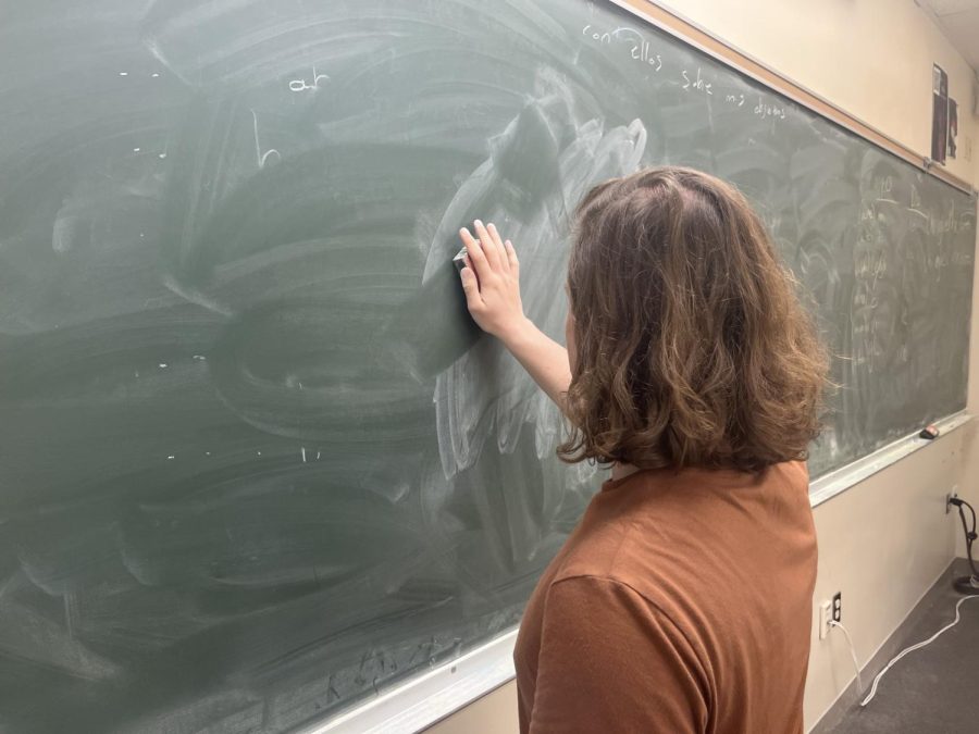 A student wipes a messy but blank chalkboard.