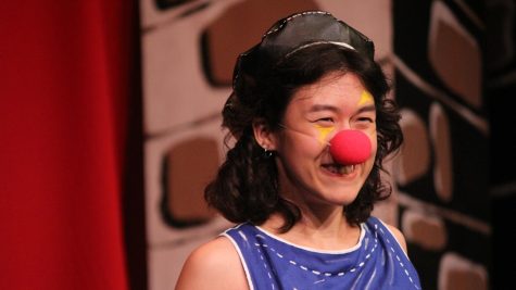 girl smiles onstage with clown nose