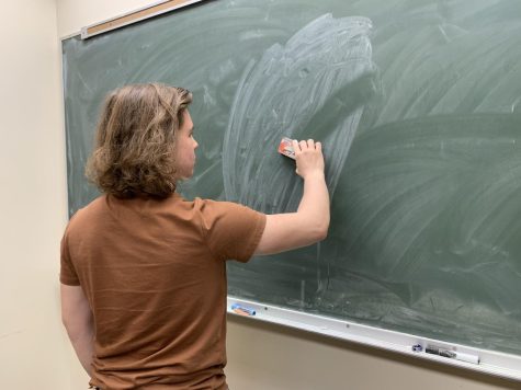 Student wiping a messy but blank chalkboard.