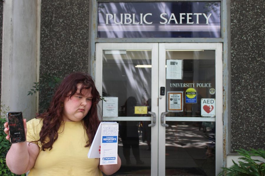 Kloe Witt stands in front of LUPD station with her reporting notebook and phone on recording.