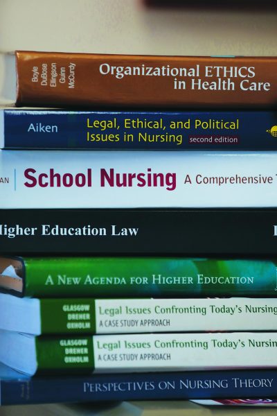 Nursing text books stacked on top of one another. Loyolas College of Nursing and Health was awarded a grant to expand therapy services.