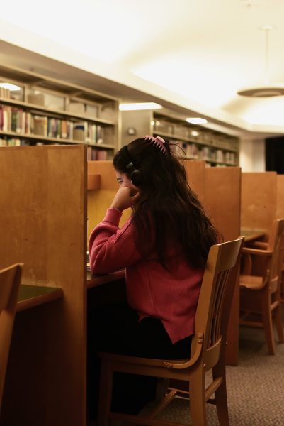 Photo Illustration of student studying in library. Library will no longer be open for 24 hours during finals week.