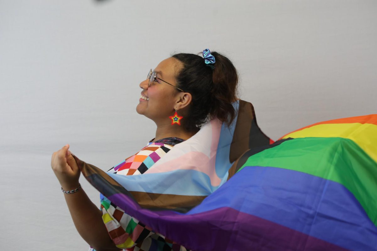 English junior Maleigh Crespo holds progress pride flag behind her. 