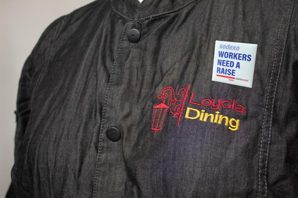 Loyola+Dining+Sodexo+worker+in+uniform+with+a+pin+saying+Sodexo+workers+need+a+raise.+