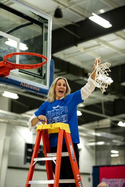 Head womens basketball coach Kellie Kennedy celebrating her 13th career title by removing the basketball net at the end of the championship game.