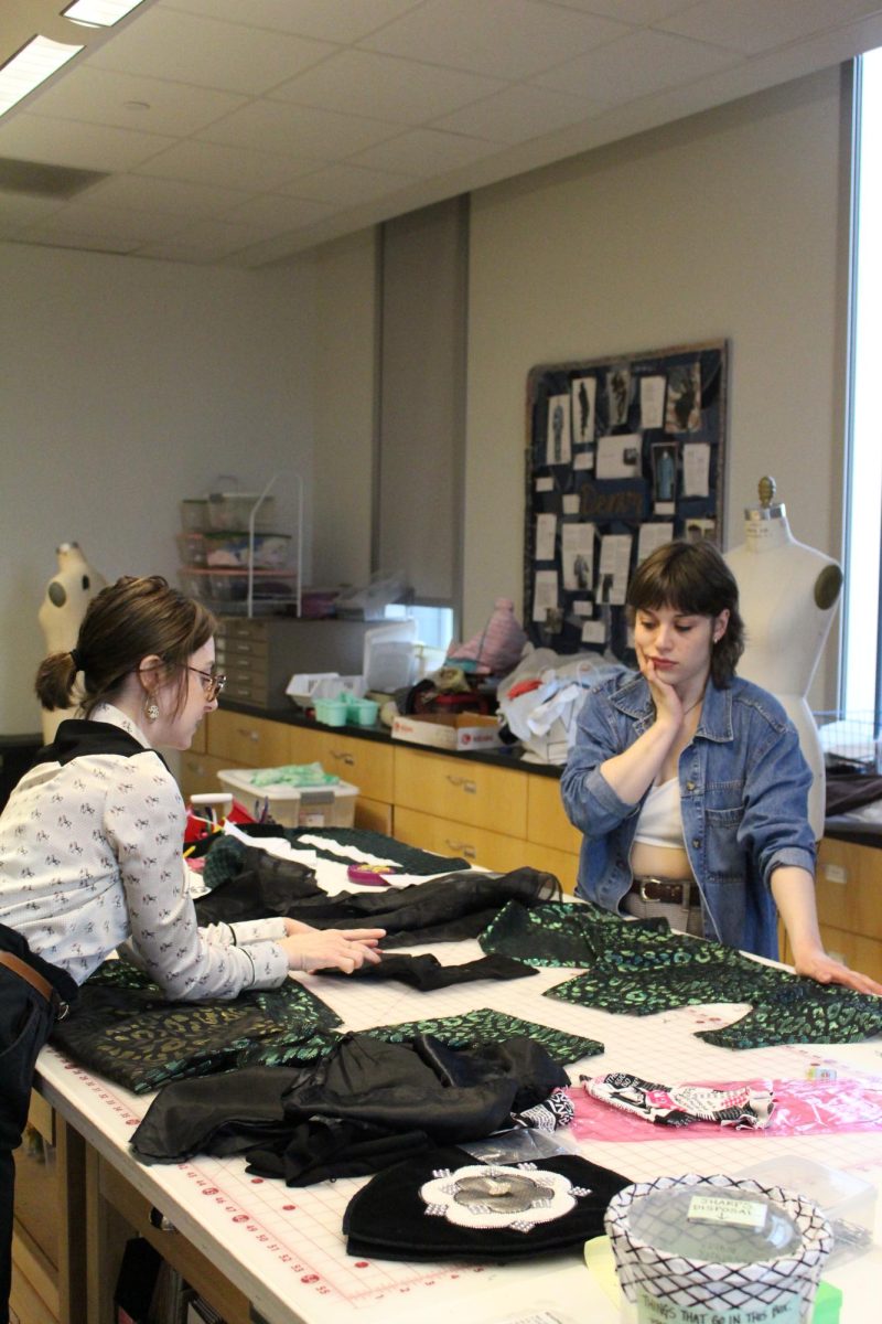 Professor and costume designer Kacie Thomassie instructs student about fabric scraps. 