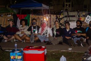 Eleven student protestors remain sitting in front of the encampment structure as police swarm the area. All 11 of them were arrested.